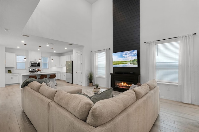 15133 Summer Harvest St, Winter Garden, FL 34787 - living room featuring a high ceiling, light wood-type flooring, a large fireplace, and recessed lighting