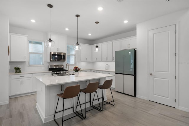 15133 Summer Harvest St, Winter Garden, FL 34787 - kitchen with appliances with stainless steel finishes, a center island with sink, light wood-type flooring, light countertops, and white cabinets