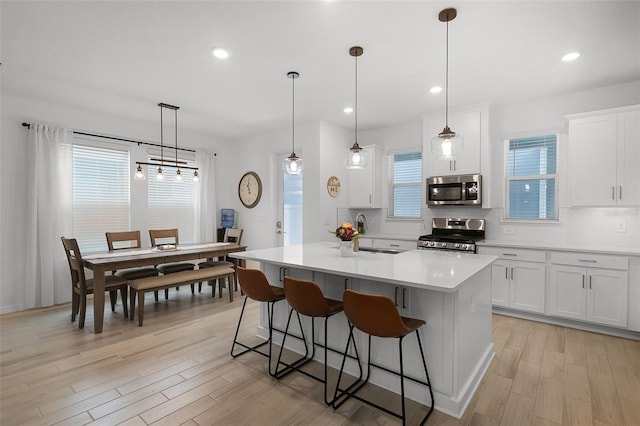 15133 Summer Harvest St, Winter Garden, FL 34787 - kitchen with appliances with stainless steel finishes, a kitchen breakfast bar, light wood-type flooring, light countertops, and recessed lighting