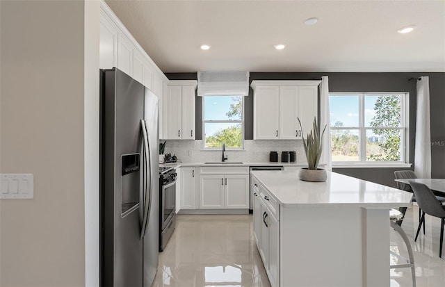 13533 Pearl Beach St, Winter Garden, FL 34787 - kitchen with appliances with stainless steel finishes, tasteful backsplash, a center island, light countertops, and white cabinets