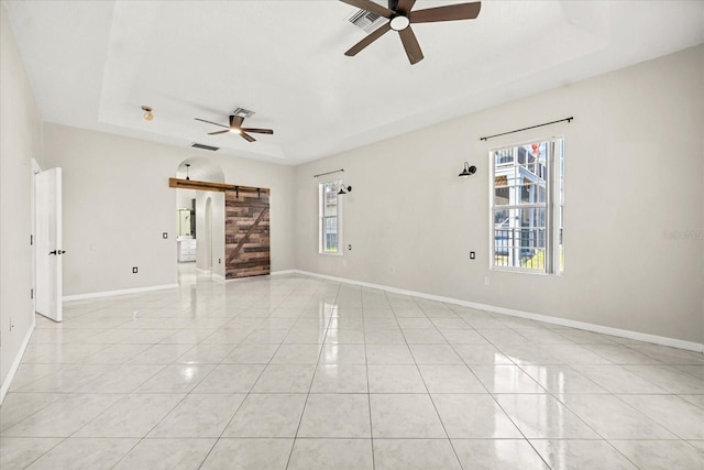 13848 Vista Del Lago Blvd, Clermont, FL 34711 - unfurnished room with a barn door, a tray ceiling, ceiling fan, and light tile patterned floors