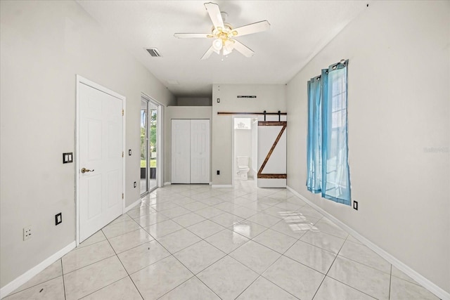 13848 Vista Del Lago Blvd, Clermont, FL 34711 - spare room with a barn door, ceiling fan, and light tile patterned flooring