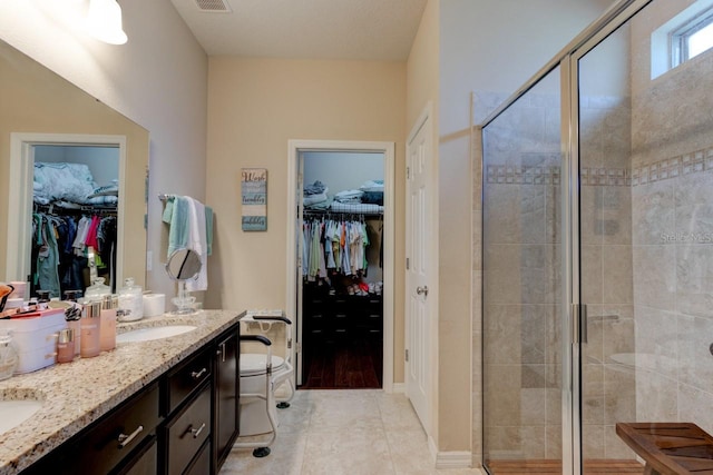 30210 Donnington Loop, Mount Dora, FL 32757 - full bathroom with double vanity, a spacious closet, a stall shower, and tile patterned flooring