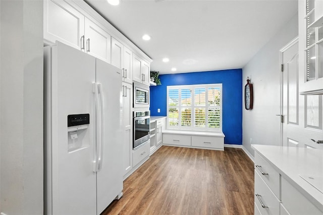 2895 Apache Ct, The Villages, FL 32163 - kitchen with stainless steel appliances, wood finished floors, white cabinets, light countertops, and recessed lighting