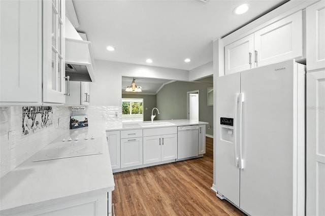 2895 Apache Ct, The Villages, FL 32163 - kitchen with white appliances, wood finished floors, light countertops, white cabinets, and tasteful backsplash