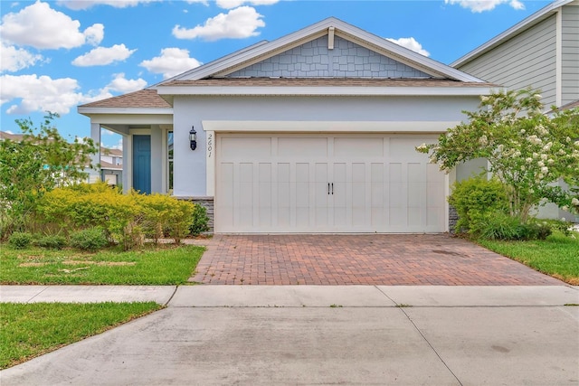 2601 Blowing Breeze Ave, Kissimmee, FL 34744 - view of front of property with decorative driveway, stone siding, roof with shingles, stucco siding, and a garage