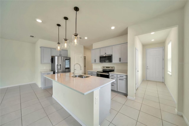 2601 Blowing Breeze Ave, Kissimmee, FL 34744 - kitchen featuring stainless steel appliances, a kitchen island with sink, light countertops, light tile patterned floors, and pendant lighting