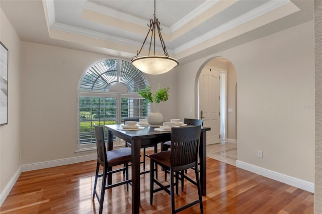 5102 Round Tree Ct, Orlando, FL 32819 - dining space featuring arched walkways, light wood-style flooring, a tray ceiling, and ornamental molding