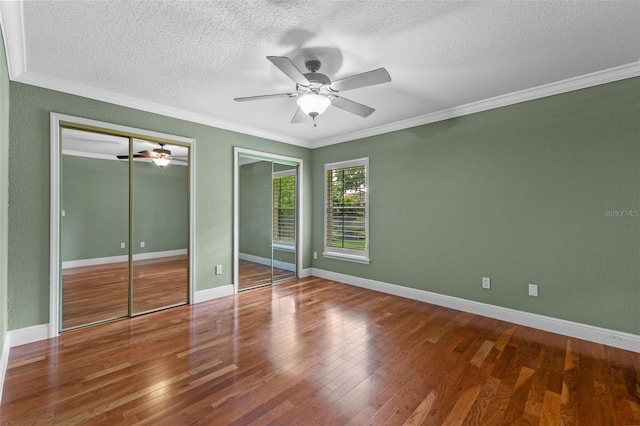 5102 Round Tree Ct, Orlando, FL 32819 - unfurnished bedroom featuring a textured ceiling, crown molding, two closets, wood finished floors, and ceiling fan