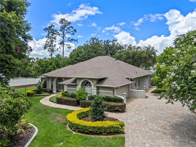 5102 Round Tree Ct, Orlando, FL 32819 - view of front of home with an attached garage, stucco siding, decorative driveway, and roof with shingles