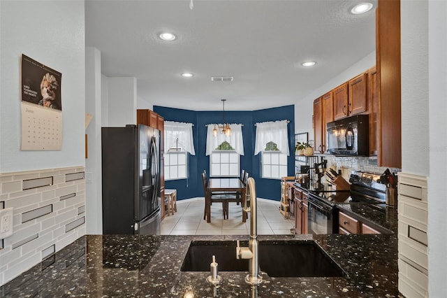 2216 Sequoia Way, Davenport, FL 33896 - kitchen featuring black appliances, brown cabinetry, light tile patterned flooring, dark stone counters, and decorative light fixtures