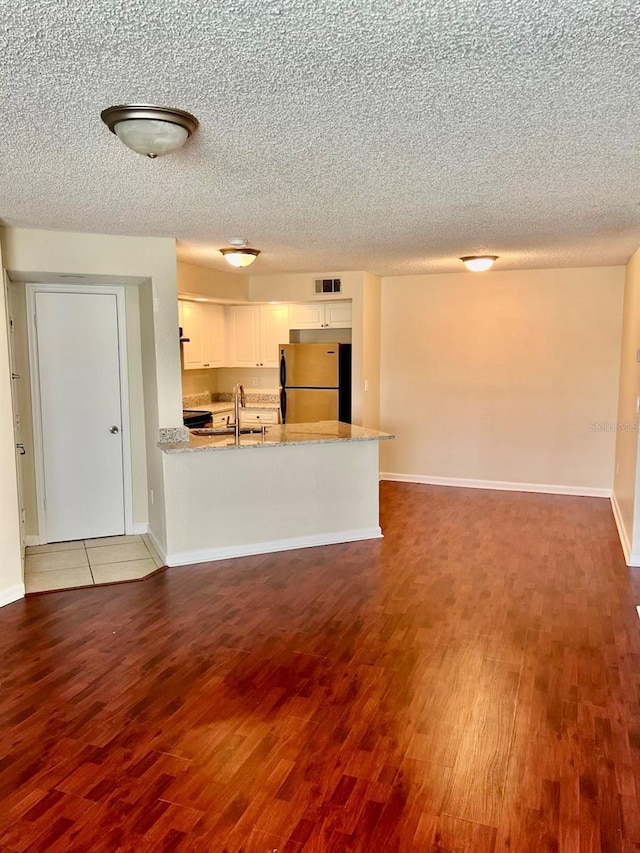 4606 Commander Dr Unit 1126, Orlando, FL 32822 - kitchen featuring freestanding refrigerator, wood finished floors, white cabinetry, a peninsula, and a textured ceiling