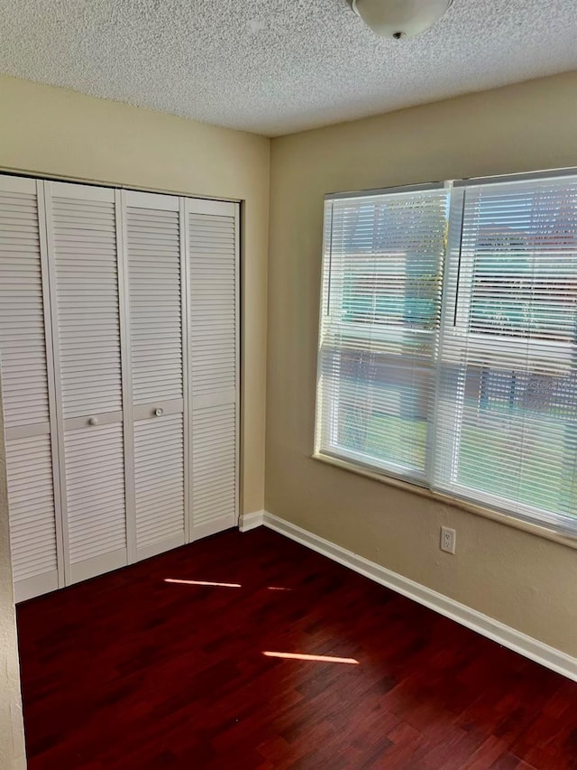 4606 Commander Dr Unit 1126, Orlando, FL 32822 - unfurnished bedroom featuring dark wood-style floors, a closet, and a textured ceiling