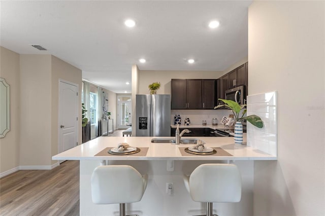 3349 Wynwood Forest Dr, Ocoee, FL 34761 - kitchen featuring appliances with stainless steel finishes, dark brown cabinetry, a breakfast bar, a peninsula, and light countertops