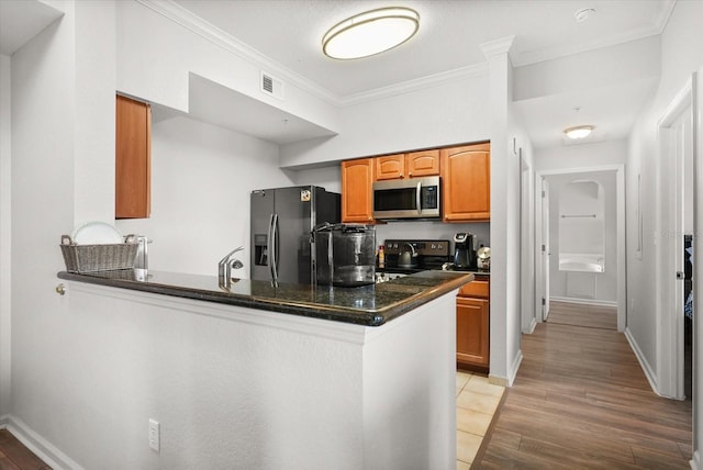 8101 Resort Village Dr Unit 31503, Orlando, FL 32821 - kitchen featuring appliances with stainless steel finishes, dark countertops, ornamental molding, light wood-type flooring, and a peninsula