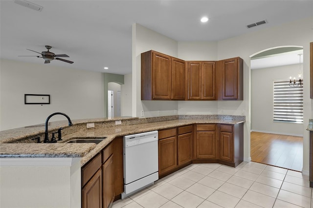 3533 Somerset Cir, Kissimmee, FL 34746 - kitchen featuring dishwasher, arched walkways, ceiling fan, light stone countertops, and brown cabinetry