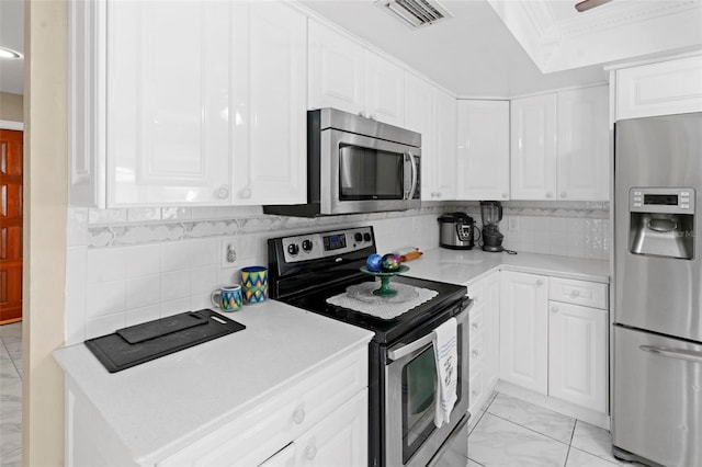 2113 Lochmoor Cir, North Fort Myers, FL 33903 - kitchen with stainless steel appliances, white cabinetry, light countertops, ornamental molding, and a raised ceiling