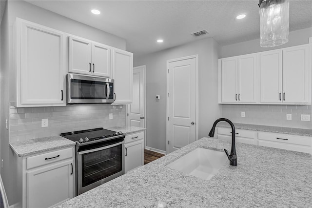840 Livestock Loop, Saint Cloud, FL 34771 - kitchen with stainless steel appliances, white cabinets, light stone countertops, recessed lighting, and a textured ceiling