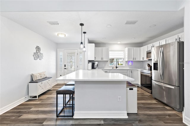 16602 Citrus Pkwy, Clermont, FL 34714 - kitchen with stainless steel appliances, a kitchen bar, a peninsula, light countertops, and dark wood finished floors