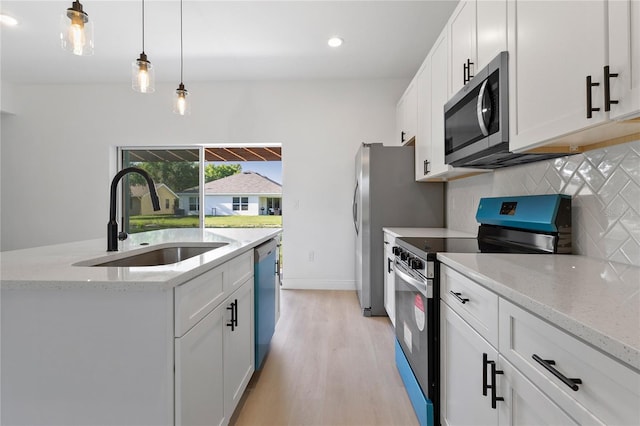 709 Marion Oaks Mnr, Ocala, FL 34473 - kitchen featuring stainless steel appliances, tasteful backsplash, light wood-style floors, white cabinets, and pendant lighting