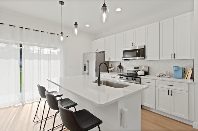 709 Marion Oaks Mnr, Ocala, FL 34473 - kitchen with appliances with stainless steel finishes, backsplash, a kitchen island with sink, white cabinets, and a kitchen bar