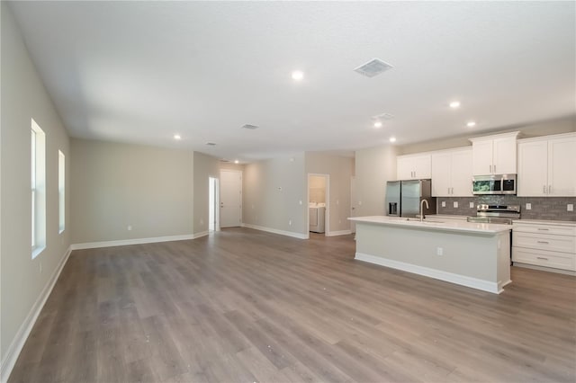 2833 E Newhaven St, Inverness, FL 34453 - kitchen with appliances with stainless steel finishes, an island with sink, tasteful backsplash, wood finished floors, and white cabinetry