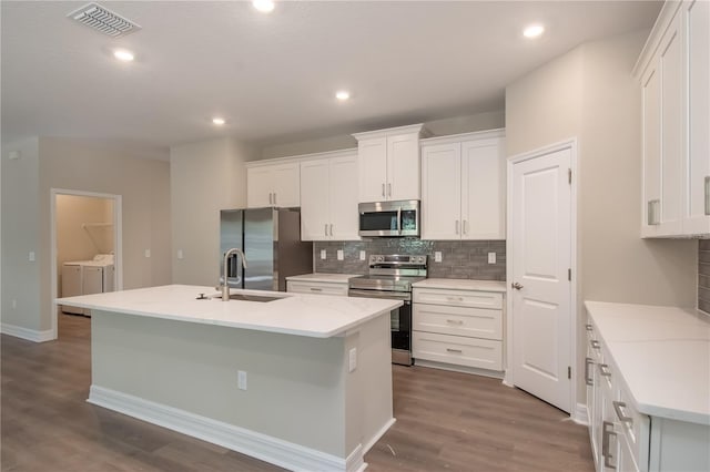 2833 E Newhaven St, Inverness, FL 34453 - kitchen with appliances with stainless steel finishes, washing machine and dryer, a kitchen island with sink, tasteful backsplash, and dark wood-type flooring
