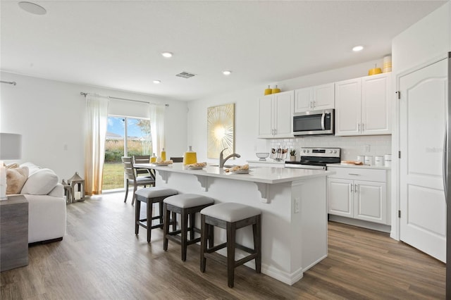 3413 Wynwood Forest Dr, Ocoee, FL 34761 - kitchen featuring appliances with stainless steel finishes, dark wood finished floors, a breakfast bar area, a center island with sink, and open floor plan