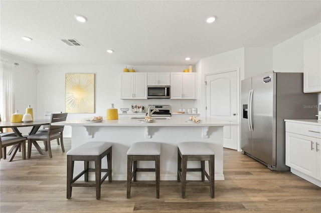 3413 Wynwood Forest Dr, Ocoee, FL 34761 - kitchen with stainless steel appliances, white cabinetry, a kitchen bar, light countertops, and recessed lighting