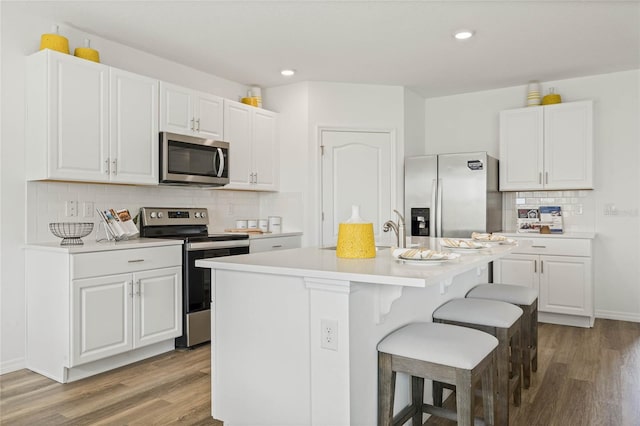 3413 Wynwood Forest Dr, Ocoee, FL 34761 - kitchen with stainless steel appliances, light wood-style floors, a breakfast bar, light countertops, and recessed lighting