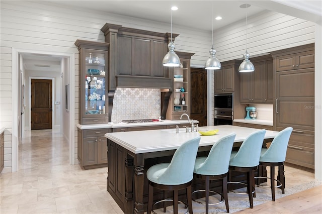 10143 Mattraw Pl, Golden Oak, FL 32836 - kitchen with light countertops, a center island with sink, decorative backsplash, a breakfast bar area, and recessed lighting