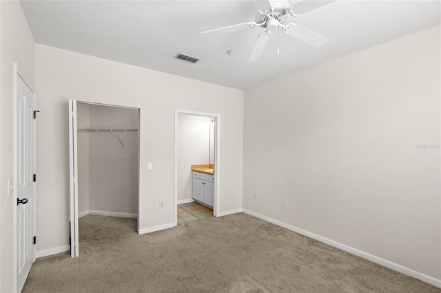 12843 Madison Pointe Unit 208, Orlando, FL 32821 - unfurnished bedroom featuring light colored carpet, a spacious closet, a closet, ceiling fan, and ensuite bath
