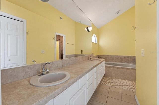 5704 Bay Side Dr, Orlando, FL 32819 - full bath with tile patterned floors, double vanity, tiled bath, and vaulted ceiling