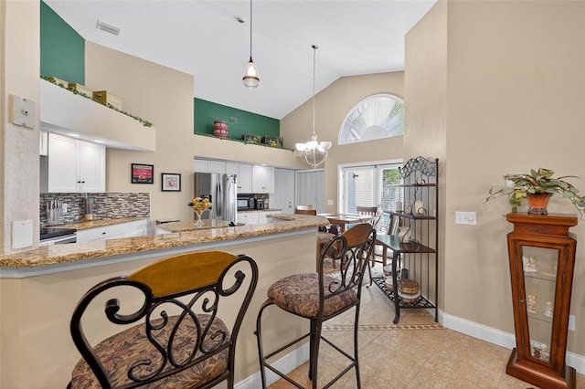5704 Bay Side Dr, Orlando, FL 32819 - kitchen featuring high vaulted ceiling, stainless steel fridge, white cabinets, light stone counters, and light tile patterned floors