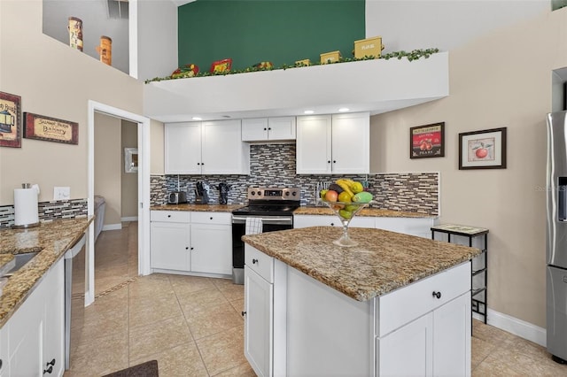 5704 Bay Side Dr, Orlando, FL 32819 - kitchen with appliances with stainless steel finishes, a towering ceiling, decorative backsplash, white cabinetry, and light stone counters