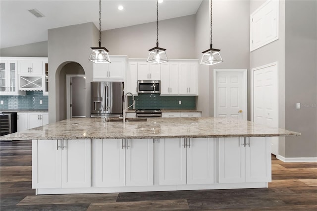 2865 Ashton Ter, Oviedo, FL 32765 - kitchen with appliances with stainless steel finishes, high vaulted ceiling, white cabinetry, decorative backsplash, and a spacious island