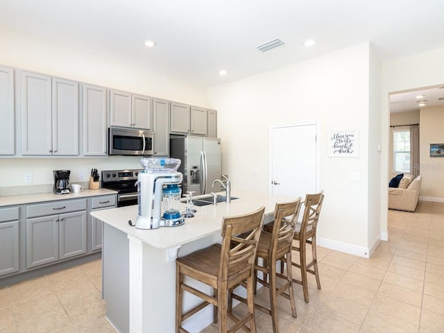 3004 Latitude Ln, Kissimmee, FL 34747 - kitchen featuring appliances with stainless steel finishes, gray cabinetry, light tile patterned floors, a kitchen bar, and recessed lighting