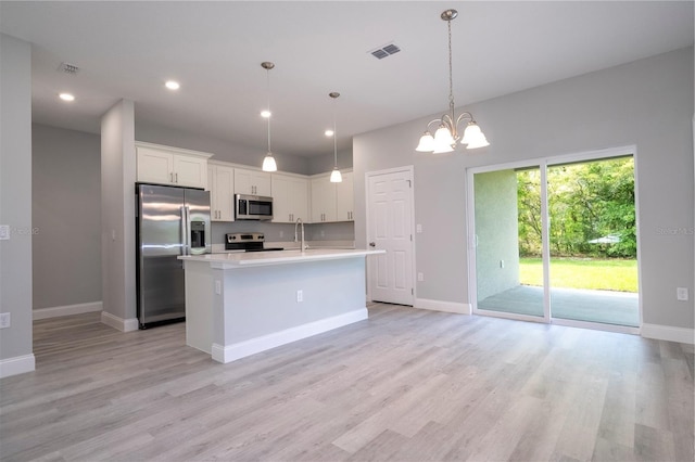 kitchen featuring appliances with stainless steel finishes, light countertops, white cabinetry, light wood-style floors, and a chandelier