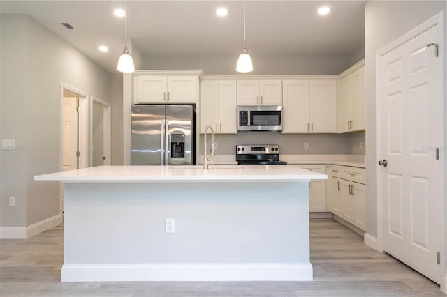 kitchen featuring appliances with stainless steel finishes, a kitchen island with sink, light countertops, recessed lighting, and white cabinets
