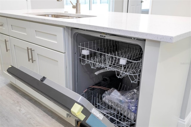 kitchen view of white cabinetry, light stone counters, wine cooler, and light wood-style flooring