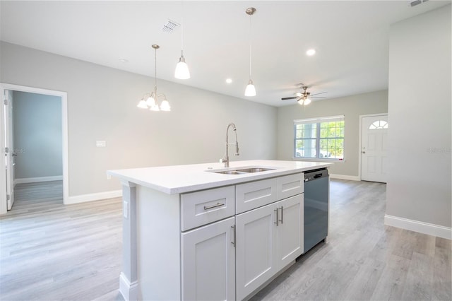 kitchen featuring dishwashing machine, light wood-style floors, light countertops, hanging light fixtures, and an island with sink