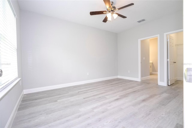 empty room with healthy amount of natural light, a ceiling fan, and light wood-type flooring