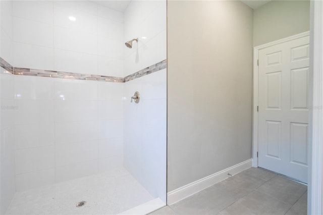 full bath with a tile shower and baseboards