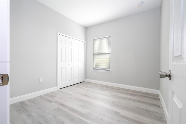 unfurnished bedroom with light wood finished floors and a closet