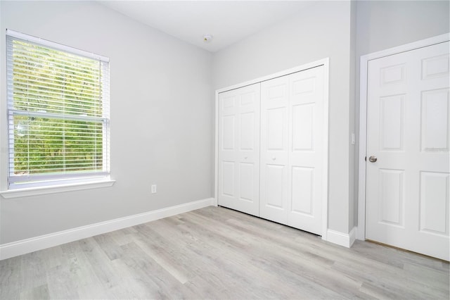 unfurnished bedroom with multiple windows, wood finished floors, and a closet