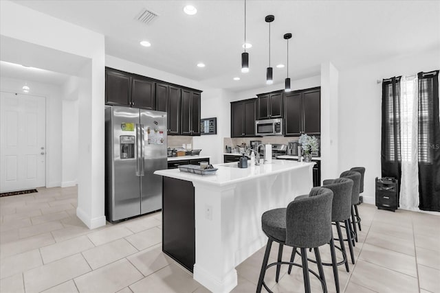 1156 Cavender Creek Rd, Minneola, FL 34715 - kitchen featuring stainless steel appliances, light countertops, pendant lighting, an island with sink, and a breakfast bar area