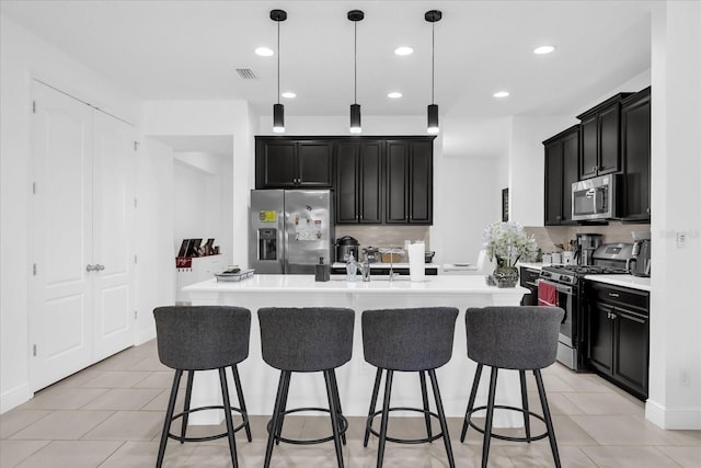 1156 Cavender Creek Rd, Minneola, FL 34715 - kitchen with appliances with stainless steel finishes, dark cabinetry, a kitchen bar, and recessed lighting
