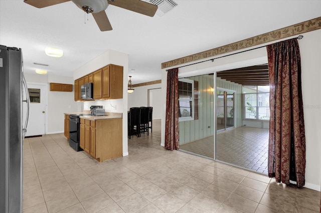 14402 SW 34th Terrace Rd, Ocala, FL 34473 - kitchen with stainless steel appliances, light countertops, light tile patterned flooring, a ceiling fan, and brown cabinetry