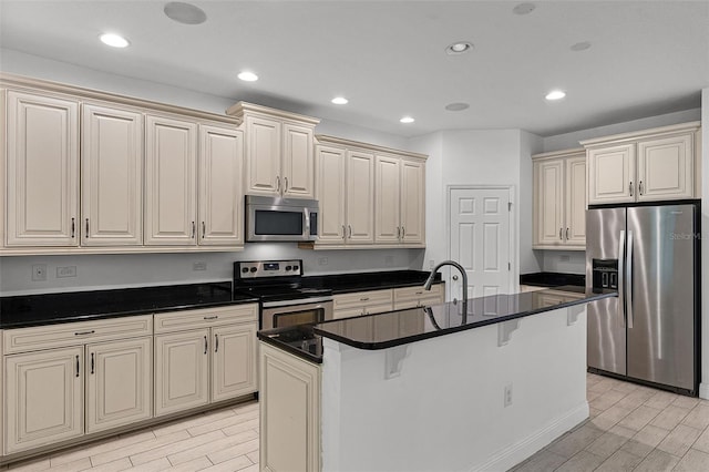 11837 Cave Run Ave, Windermere, FL 34786 - kitchen featuring stainless steel appliances, cream cabinets, wood finish floors, recessed lighting, and an island with sink