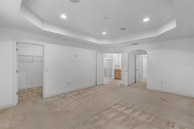 11837 Cave Run Ave, Windermere, FL 34786 - unfurnished bedroom featuring a raised ceiling, arched walkways, light carpet, a walk in closet, and recessed lighting